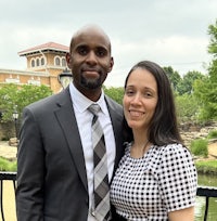 a man and woman posing for a photo in front of a pond