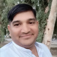 a man in a white shirt smiling in front of a tree